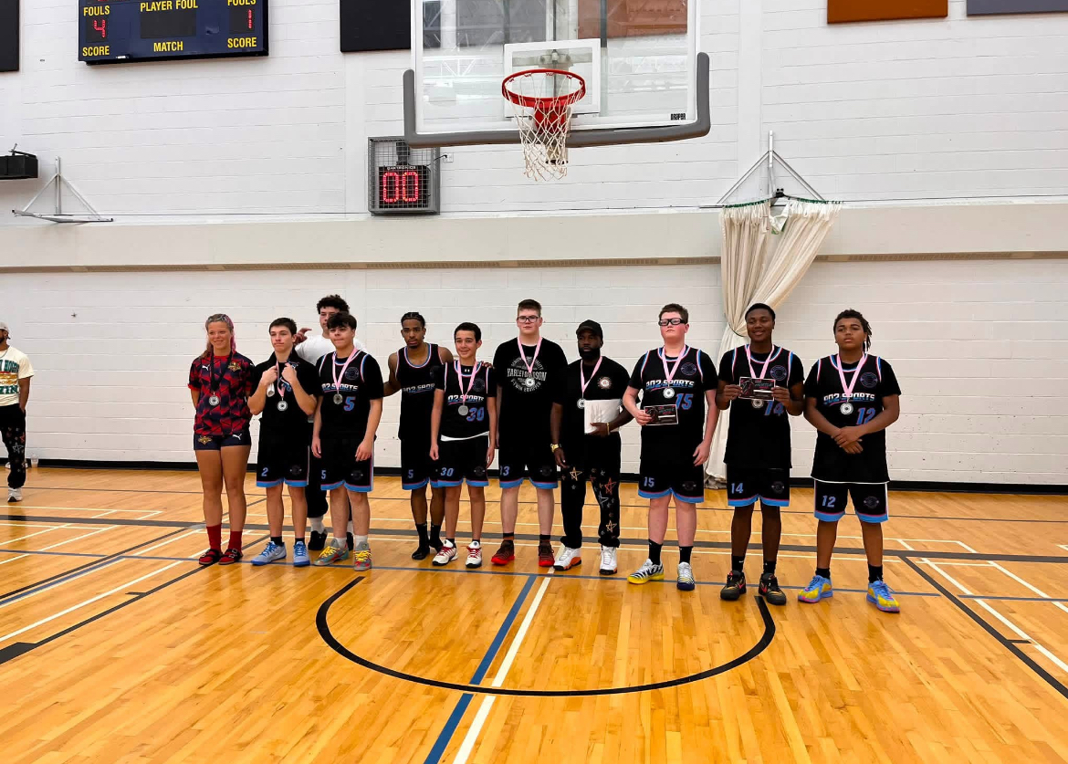 The 902 Scotian Sports team and coaches posing with medals and awards on the court